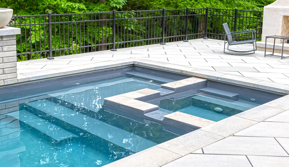 Leisure Pools Limitless fiberglass swimming pool with built-in spa and splash deck