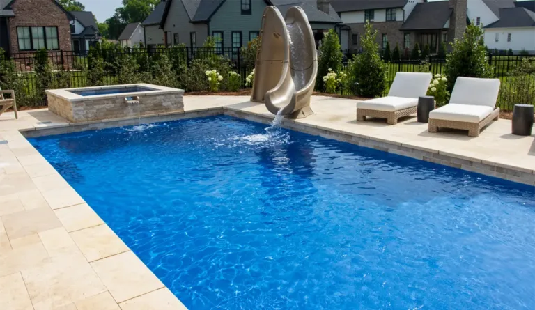 Leisure Pools Pinnacle fiberglass pool with pool slide and large patio surround