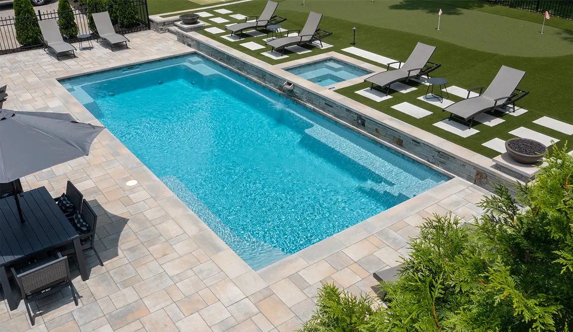 The Supreme rectangular fiberglass pool with lounge chairs and tanning ledge