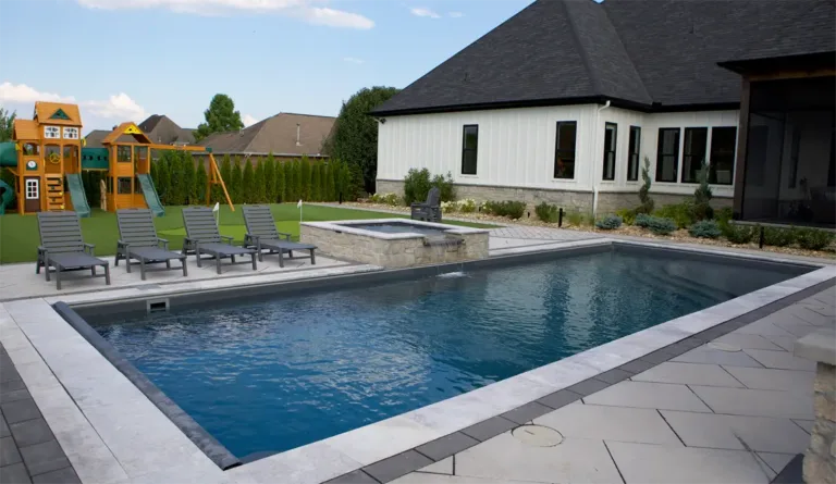 Leisure Pools Wave fiberglass pool with raised spa and lounge chairs on splash deck