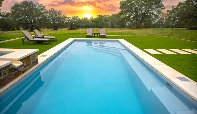 Leisure Pools Wave fiberglass pool with open field and vibrant sunset backdrop