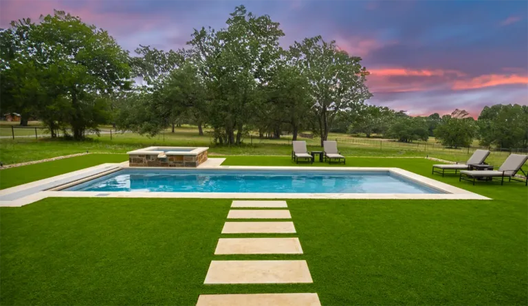 The Wave fiberglass pool with mature oak trees and dramatic dusk sky backdrop