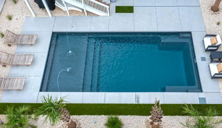 The Summit compact fiberglass pool in Graphite Grey with clean white patio surround