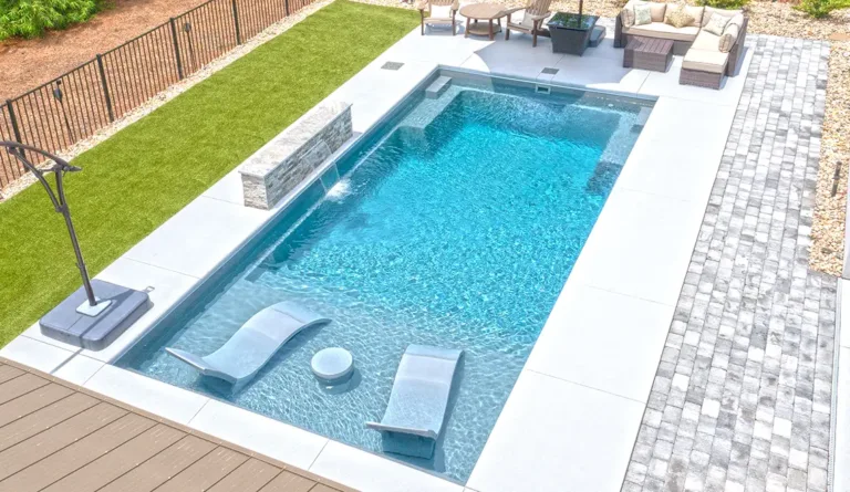 The Summit fiberglass pool aerial view showing full-width splash deck with lounge chairs in Graphite Grey
