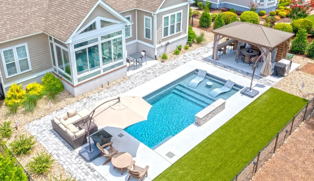 Leisure Pools Summit fiberglass pool in Graphite Grey installed with coastal home and sunroom backdrop