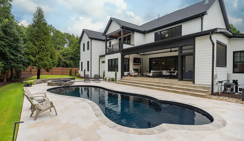 Leisure Pools Eclipse fiberglass pool in Ebony Blue with modern home and patio surround