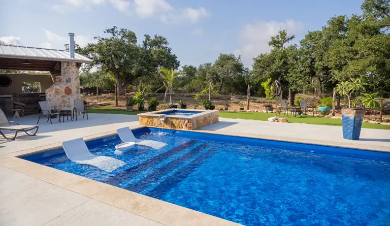 The Pinnacle fiberglass pool in Sapphire Blue with raised spa and outdoor kitchen
