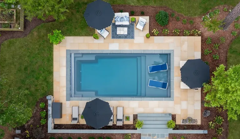 The Summit 30 fiberglass pool aerial overhead view with patio umbrella and furniture in Graphite Grey