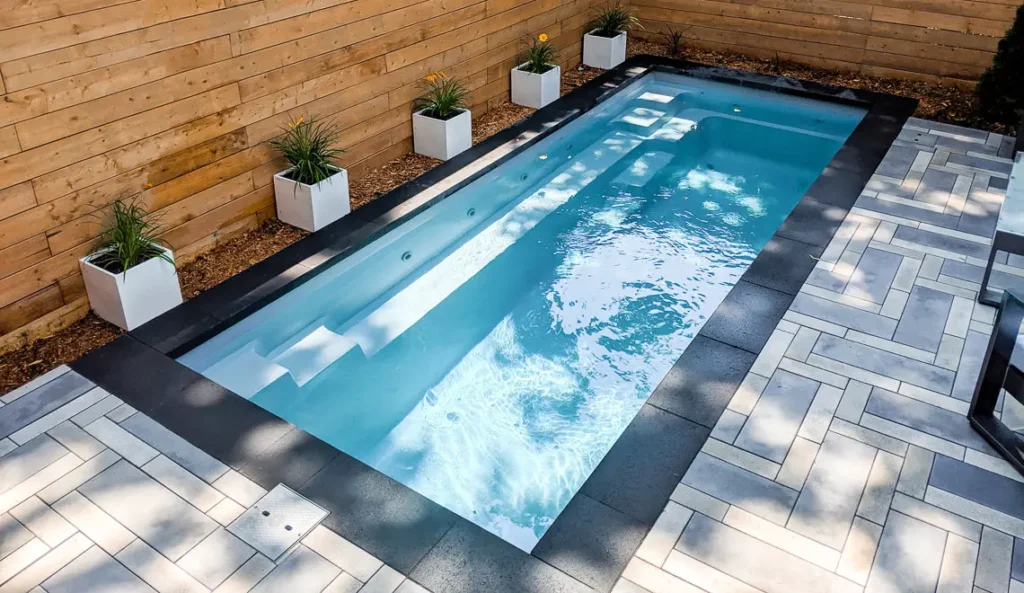 Leisure Pools Esprit fiberglass pool with spa jets active and timber fence surround