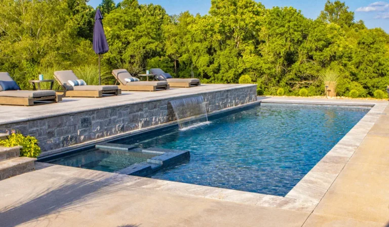 Leisure Pools Limitless fiberglass pool with water feature spillover and open backyard