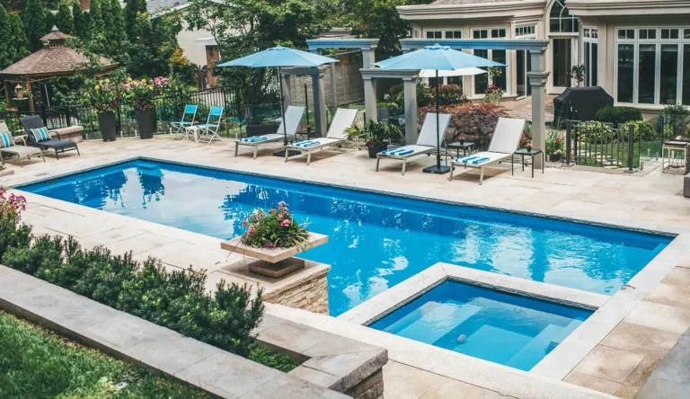 Leisure Pools Ultimate fiberglass pool in Crystal Blue with built-in spa and poolside lounge seating