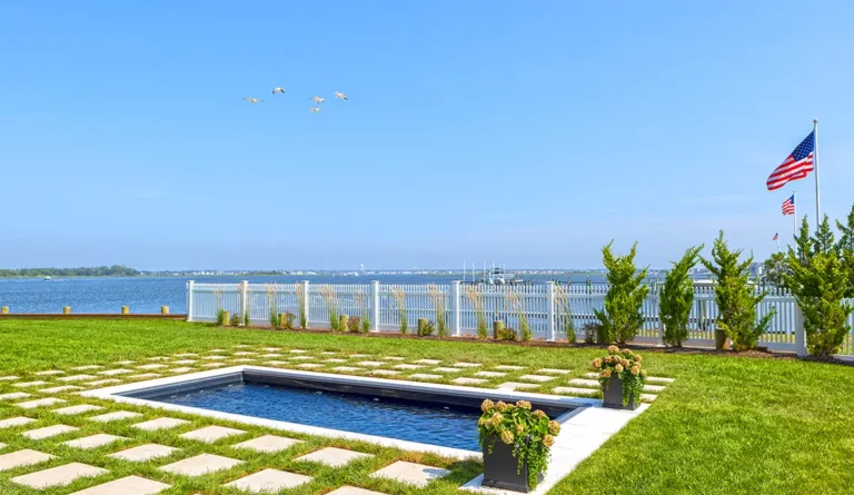 Leisure Pools Harmony 20 fiberglass pool in Ebony Blue with open waterfront bay backdrop