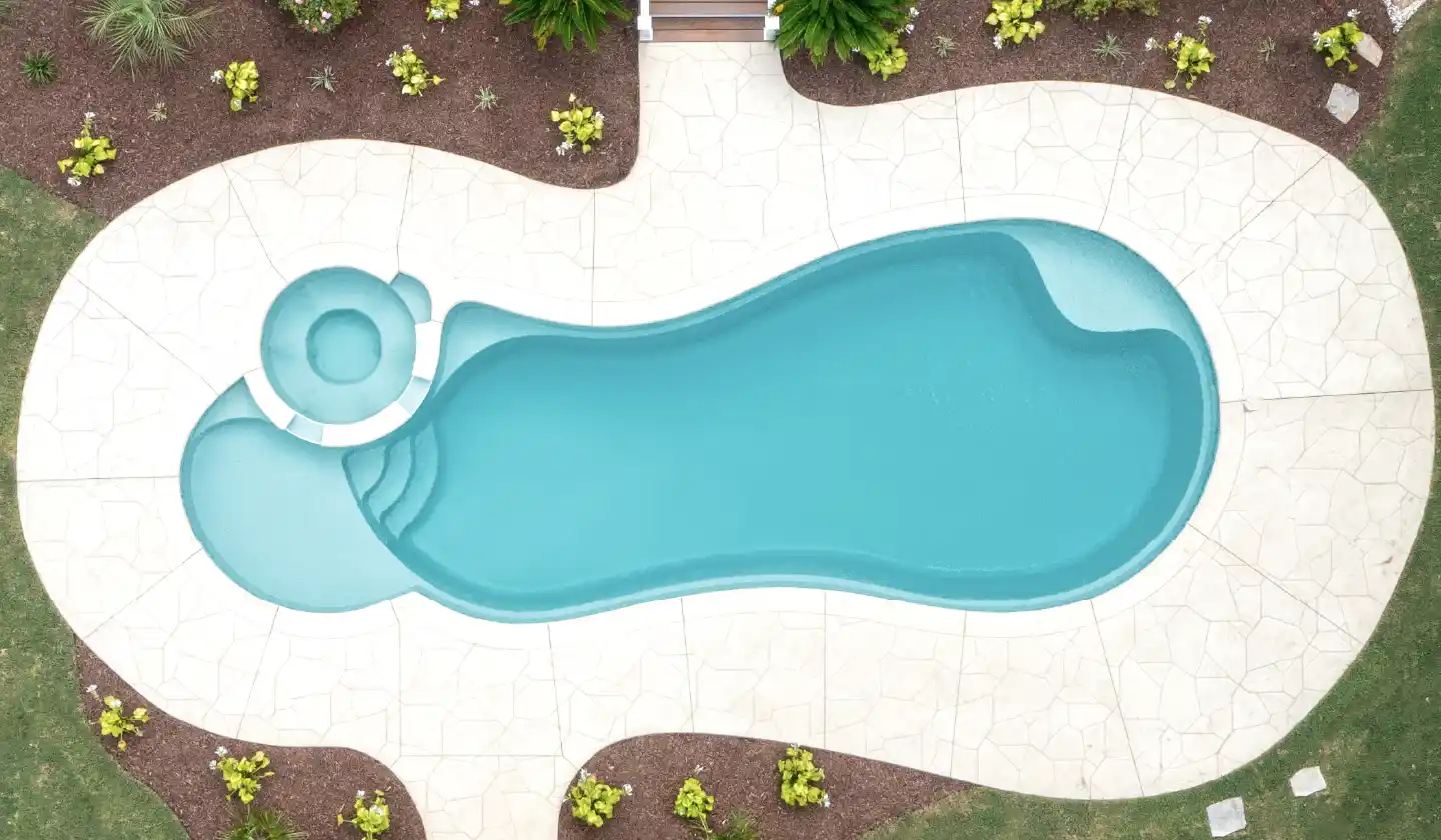 The Allure™ in Diamond Sand, a fiberglass pool with a flowing outline, built-in spa and splash deck at one end.