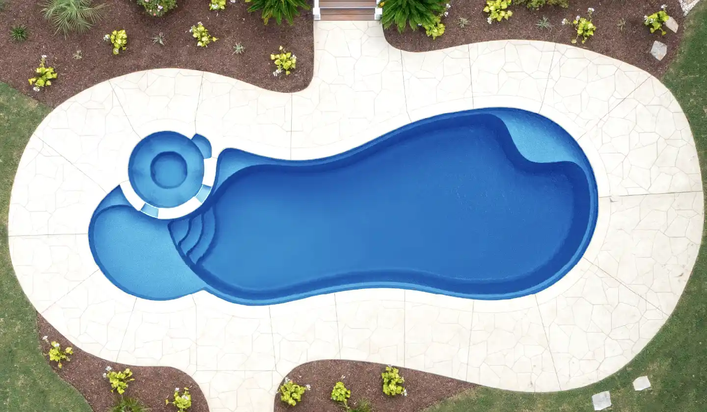 The Allure™ fiberglass pool in Sapphire Blue, featuring a freeform swimming corridor framed by pale stone paving.