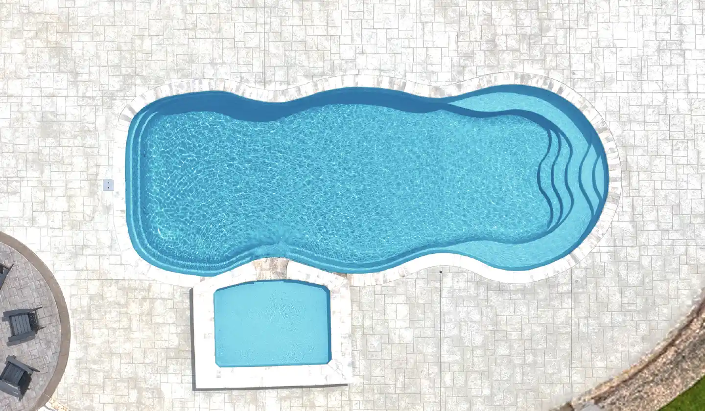 The Caribbean™ in Crystal Blue, a fiberglass pool with flowing pool edges surrounding an open swim corridor.