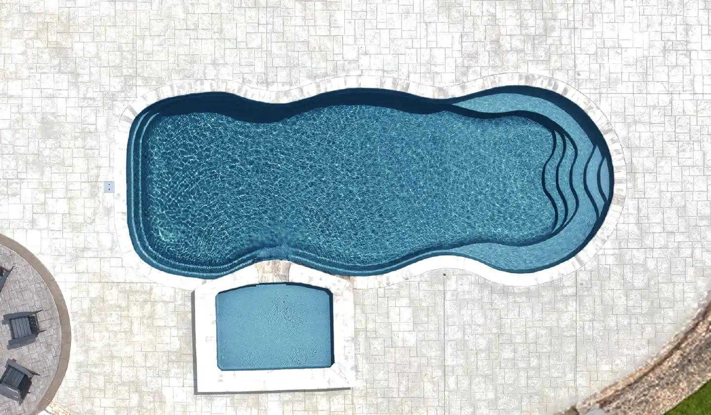 Overhead view of The Caribbean™ fiberglass pool in Ebony Blue, with a gently undulating outline and broad shallow-end steps.