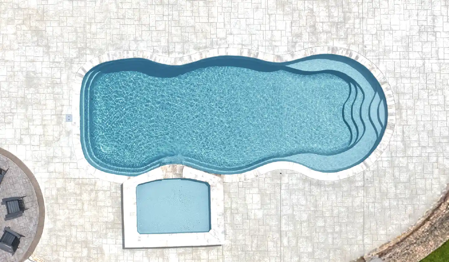 The Caribbean™ fiberglass pool in Silver Grey, with an unobstructed swim channel and curved shallow-end seating.