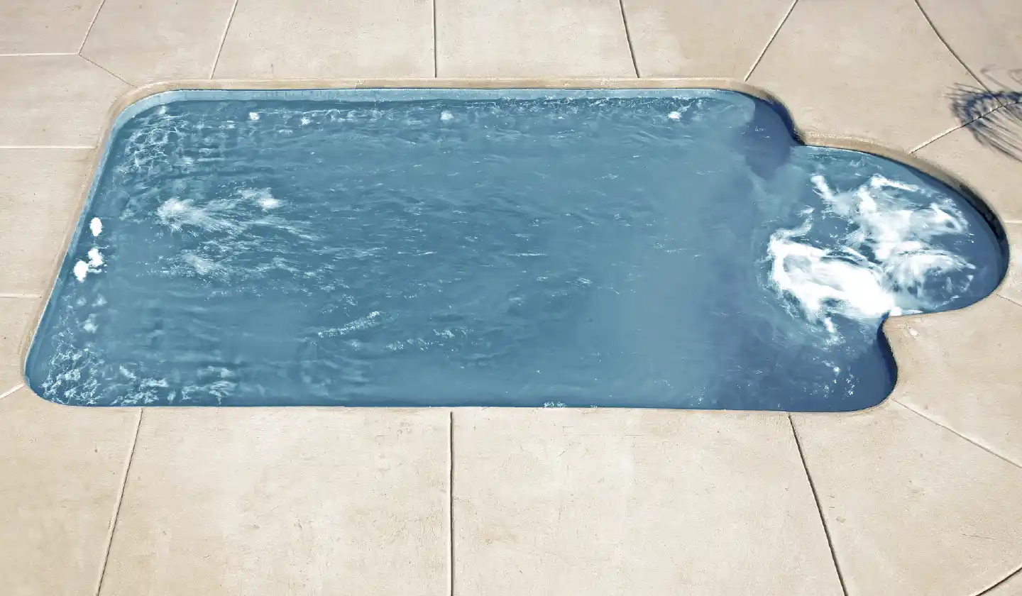 Elevated view of The Courtyard Roman™ fiberglass pool in Silver Grey, with an open swimming area adjoining the curved spa seating nook.