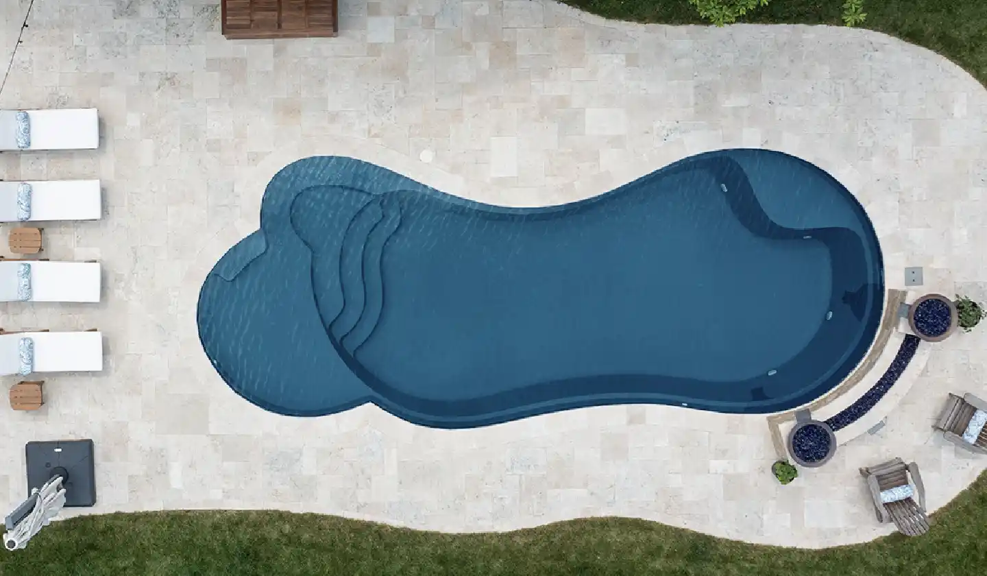 The Eclipse™ in Ebony Blue, a fiberglass pool with a freeform shape, integrated splash deck and swim-out seating.