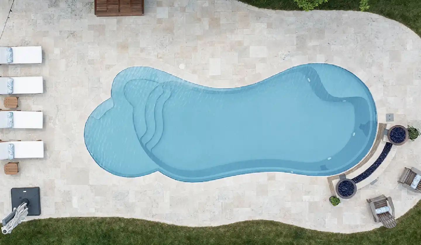 The Eclipse™ fiberglass pool in Shimmer Sky, featuring a broad lounging deck within a gently curving pool outline.