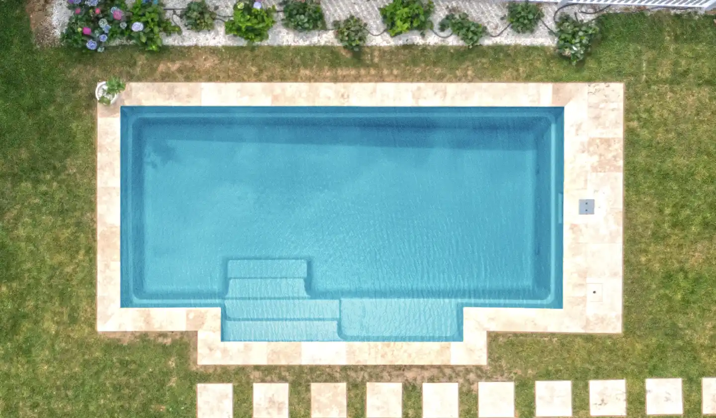 Overhead view of The Elegance™ fiberglass pool in Crystal Blue, with a projecting entry area and built-in bench seating.