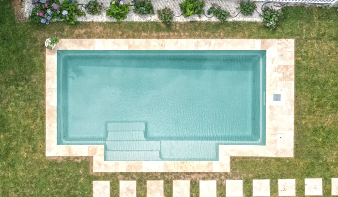 The Elegance™ fiberglass pool in Diamond Sand, featuring a straight-sided swimming area bordered by pale paving and lawn.