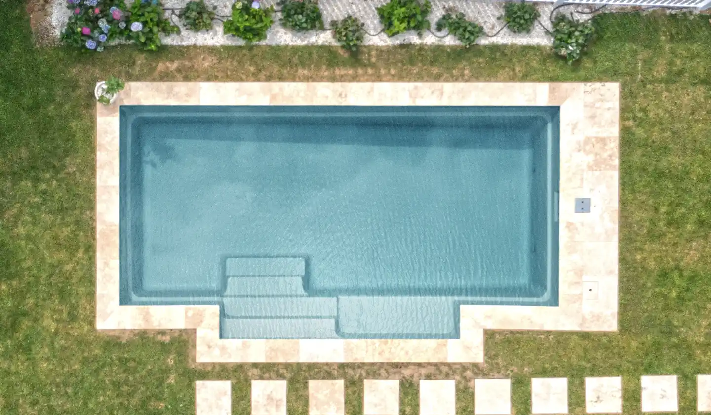 The Elegance™ in Silver Grey, a fiberglass pool with a long swimming corridor framed by a built-in seating nook.