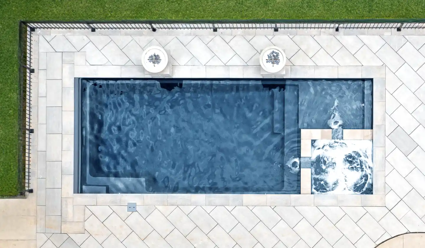 The Limitless™ in Ebony Blue, a fiberglass pool with a compact rectangular shape, splash deck and built-in spa.