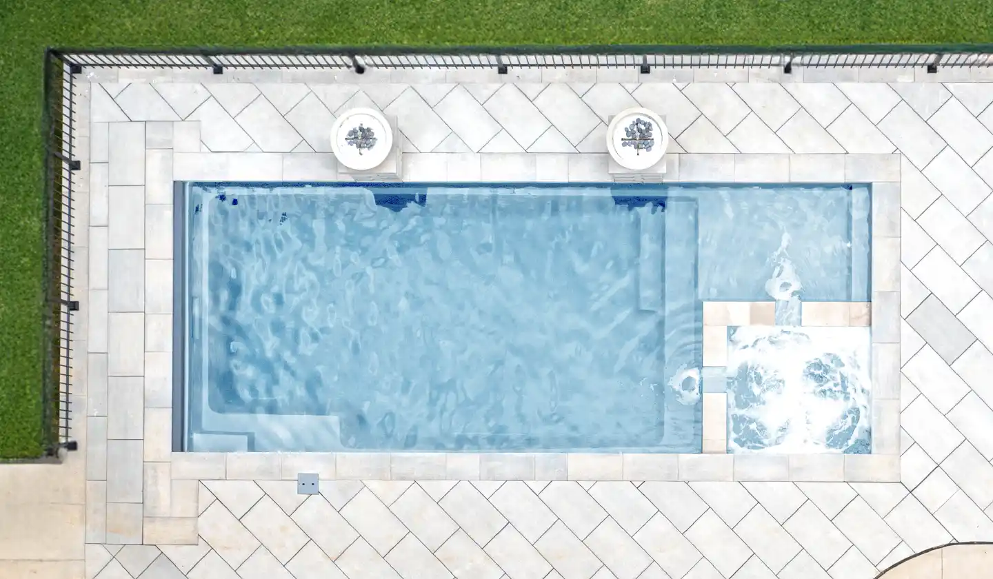 The Limitless™ fiberglass pool in Shimmer Sky, featuring a straight swim corridor opening beside the spa and lounging shelf.