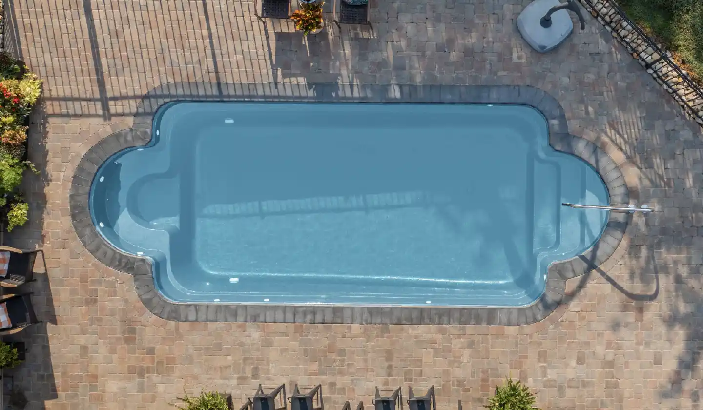 Overhead view of The Roman™ fiberglass pool in Shimmer Sky, with built-in benches within a classical rounded pool outline.