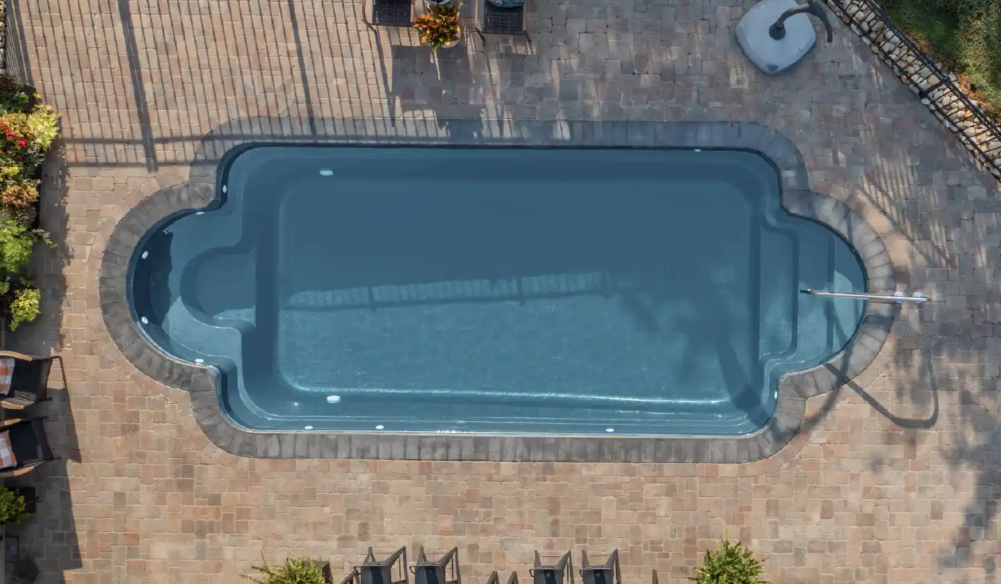 The Roman™ fiberglass pool in Silver Grey, featuring an open swim corridor bordered by curved seating recesses.