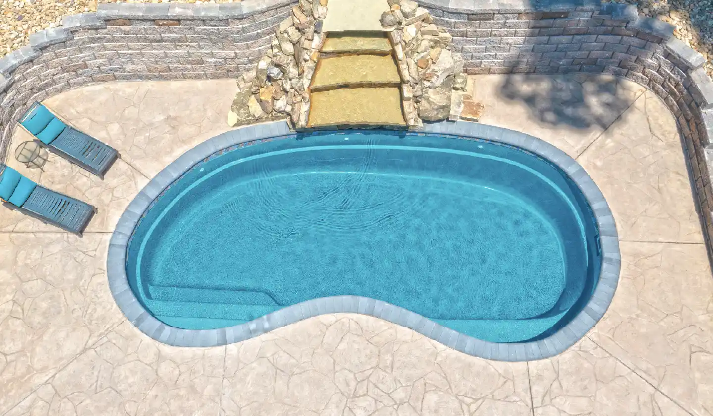 The Tuscany™ in Aquamarine, a fiberglass pool with a kidney-shaped swimming area and integrated entry steps.