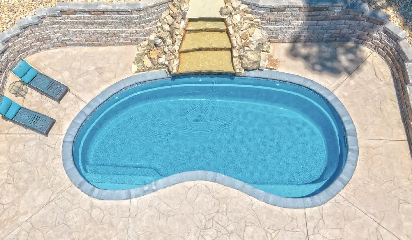 The Tuscany™ shown in Crystal Blue, featuring a curved swim corridor surrounded by a stone patio.