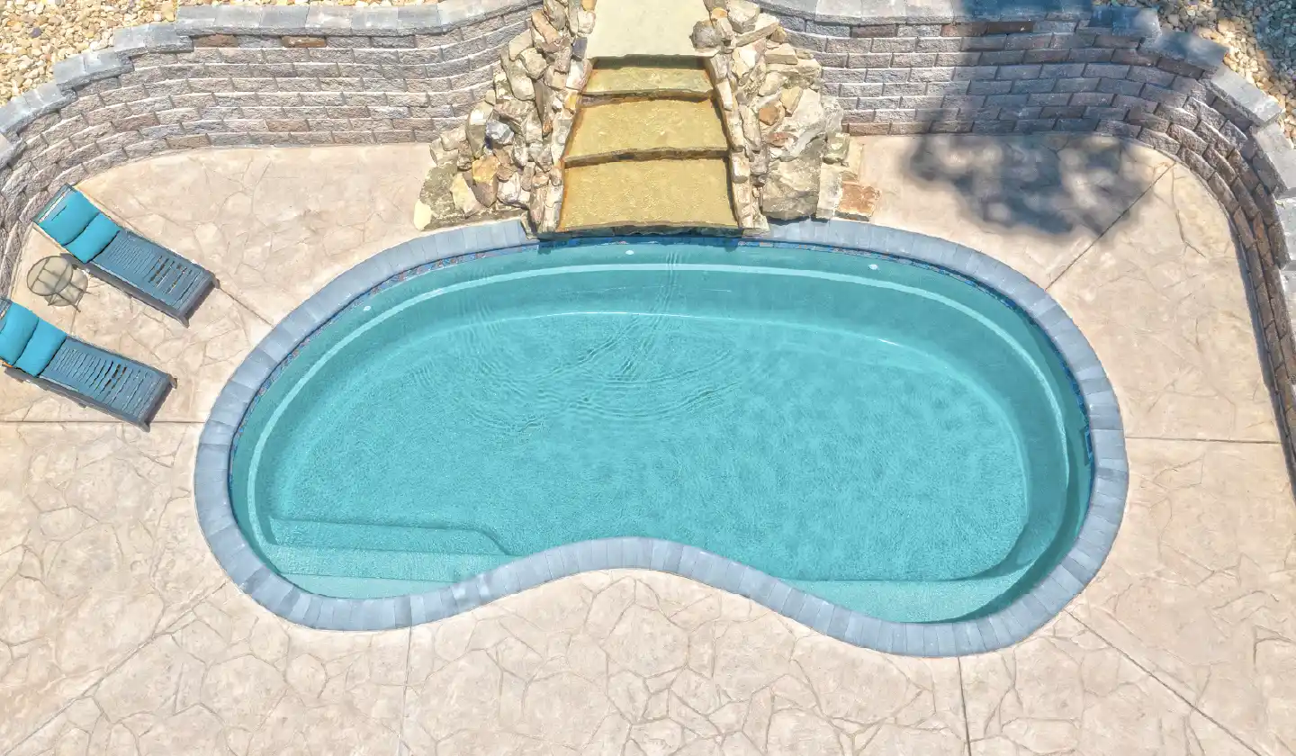 Elevated view of The Tuscany™ fiberglass pool in Diamond Sand, with a rounded pool outline beneath a garden stairway.