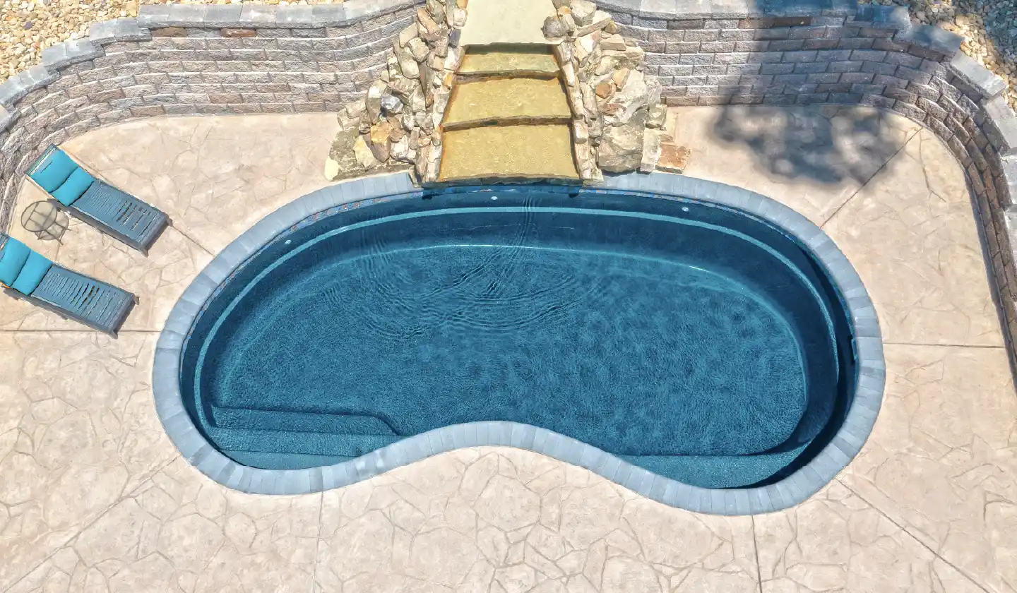 The Tuscany™ fiberglass pool in Ebony Blue, featuring a kidney shape, built-in steps and deep-end swim-out seating.