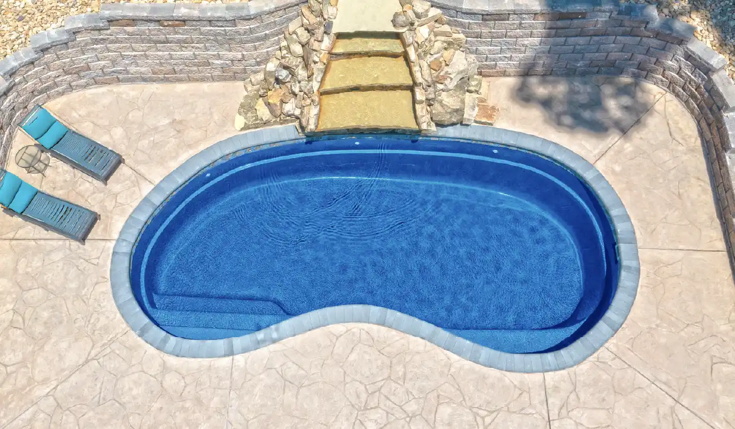 Elevated view of The Tuscany™ in Sapphire Blue, showing a kidney-shaped pool bordered by pale coping and stonework.